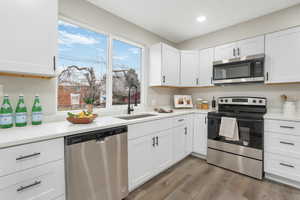 Kitchen featuring sink, stainless steel appliances, light hardwood / wood-style floors, and white cabinets