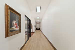 Corridor with a skylight and light hardwood / wood-style floors