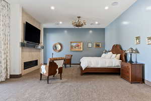 Bedroom with light carpet, a tiled fireplace, and a chandelier