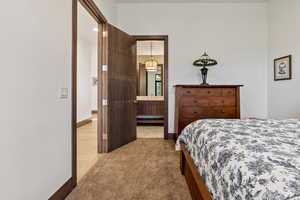 Bedroom featuring ensuite bath, a baseboard radiator, and light colored carpet