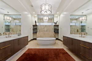 Bathroom featuring vanity, a notable chandelier, and a tub to relax in