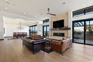 Living room featuring an inviting chandelier, a large fireplace, and light wood-type flooring