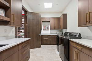 Laundry area featuring cabinets, independent washer and dryer, and a skylight