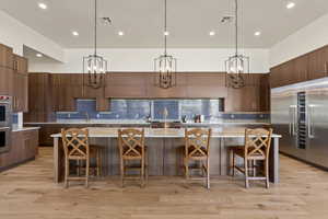 Kitchen with stainless steel appliances, hanging light fixtures, a large island, and a kitchen bar