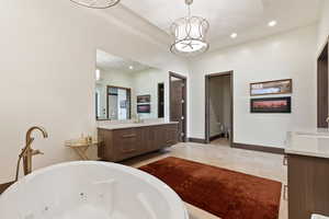 Bathroom with vanity, a tub, and a notable chandelier