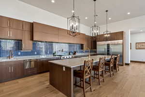 Kitchen with pendant lighting, sink, light hardwood / wood-style floors, and a spacious island