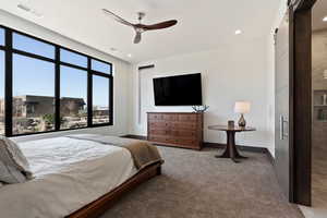 Bedroom with ceiling fan, a barn door, and carpet floors