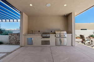 View of patio with a grill, sink, and exterior kitchen