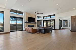 Living room with a fireplace, light hardwood / wood-style floors, ceiling fan, and plenty of natural light