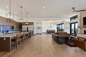 Living room with a high ceiling, a tile fireplace, an inviting chandelier, and light hardwood / wood-style floors