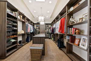 Spacious closet with light colored carpet and a chandelier