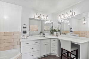 Bathroom featuring tasteful backsplash, vanity, tiled bath, and tile patterned floors