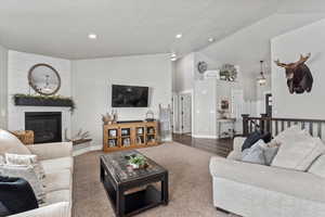 Carpeted living room featuring a fireplace and high vaulted ceiling
