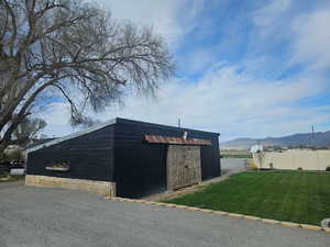 View of outbuilding with fence, a mountain view, and an outbuilding