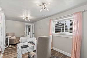 Office featuring an inviting chandelier, dark hardwood / wood-style flooring, and a textured ceiling