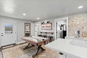 Game room featuring sink, light hardwood / wood-style floors, and a textured ceiling