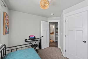 Bedroom featuring a notable chandelier and dark colored carpet