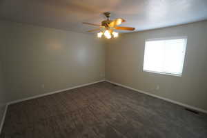 Unfurnished room featuring ceiling fan and dark colored carpet