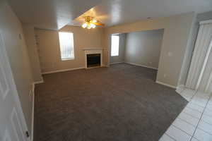 Unfurnished living room with ceiling fan and light tile patterned floors