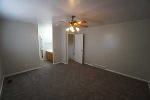 Unfurnished bedroom featuring connected bathroom, ceiling fan, and dark colored carpet