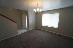 Carpeted empty room with a notable chandelier