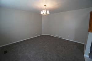 Carpeted spare room with a chandelier