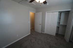 Unfurnished bedroom featuring dark colored carpet, ceiling fan, and a closet