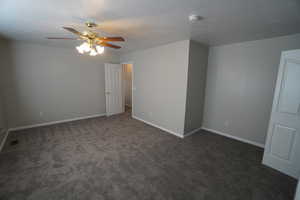 Spare room with ceiling fan and dark carpet