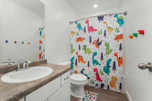 Full bathroom featuring hardwood / wood-style flooring, vanity, toilet, and shower / tub combo