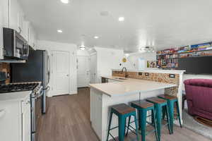 Kitchen featuring sink, white cabinetry, stainless steel appliances, a kitchen breakfast bar, and kitchen peninsula