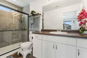 Bathroom featuring vanity, toilet, and a shower with shower door