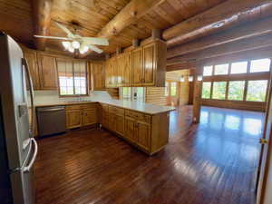 Kitchen featuring appliances with stainless steel finishes, wooden ceiling with exposed beams, a ceiling fan, plenty of natural light, and hardwood floors
