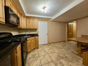Basement kitchen with black appliances & dining area