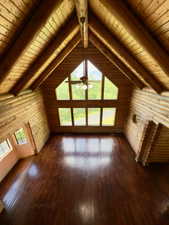 Living room with hardwood floors, wood ceiling, a ceiling fan, and log walls