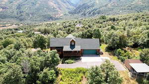 Aerial view of property and surrounding area featuring a forest and a mountain backdrop