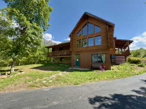 View of front of property featuring log exterior, a wooden deck, a yard, and stairway