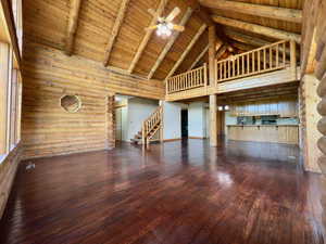 Large living room featuring high vaulted ceilings, hardwood floors, ceiling fan, and wood ceiling with exposed beams. Loft is above.