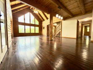 Living room with hardwood floors, lots of natural light, wooden ceiling with exposed beams, stairway, and high vaulted ceiling