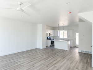 Kitchen with white cabinetry, stainless steel appliances, a center island, light hardwood / wood-style floors, and decorative light fixtures