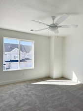 Empty room with carpet floors, a textured ceiling, and ceiling fan