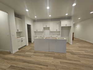 Kitchen with white cabinetry, a kitchen island, and light hardwood / wood-style flooring