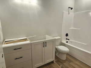 Full bathroom with wood-type flooring, toilet,  shower combination, and vanity