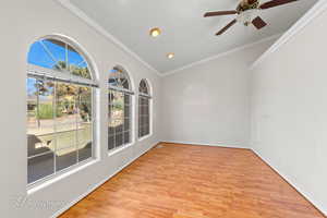 Empty room with light hardwood / wood-style flooring, ornamental molding, and ceiling fan