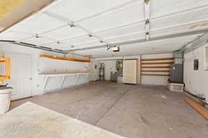 Garage with a garage door opener, heating unit, electric panel, and secured water heater