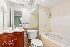 Full bathroom with vanity, toilet, tub / shower combination, and tile walls