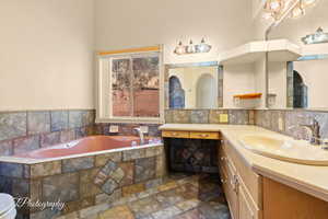 Bathroom with backsplash, vanity, and tiled tub