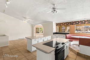 Kitchen featuring white cabinetry, black electric range oven, a center island, and ceiling fan