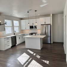 Kitchen with sink, a center island, pendant lighting, stainless steel appliances, and white cabinets