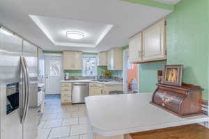 Kitchen with appliances with stainless steel finishes, a tray ceiling, sink, kitchen peninsula, and a textured ceiling