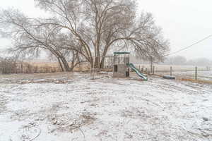 Yard layered in snow featuring a playground